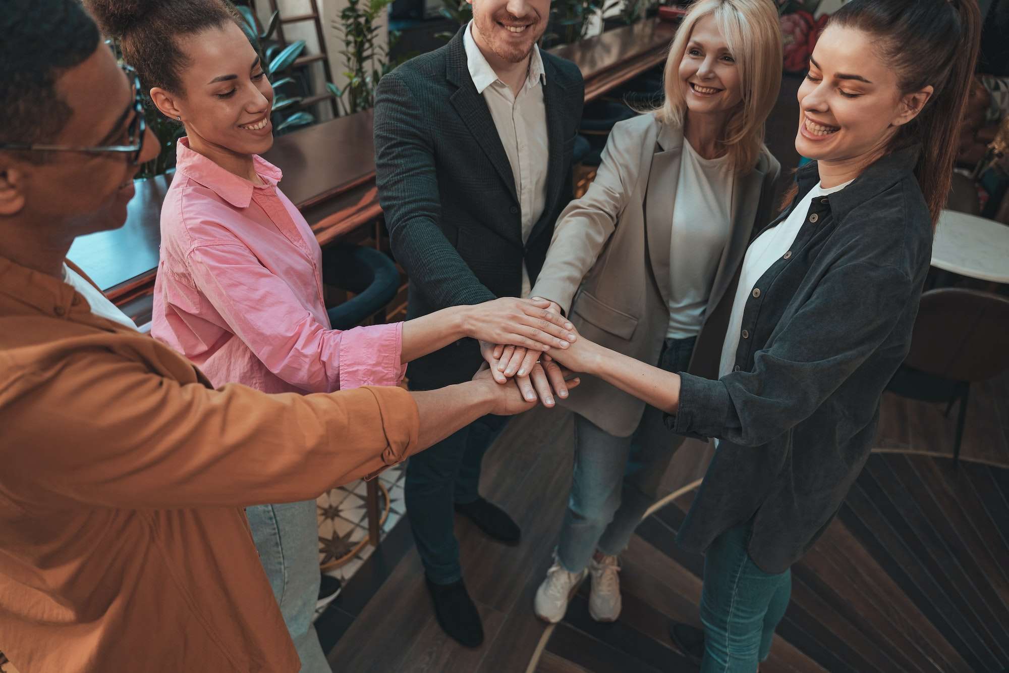 Group of coworkers stacking hands together one by one in unity. Support and motivation concept
